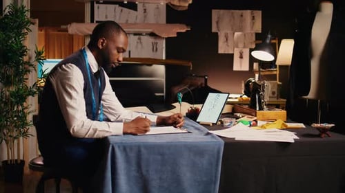 Fashion Designer Sketching Designs in Workshop