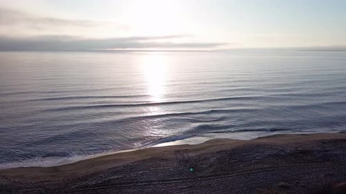 Black Sea and Beach Nearby Against a Sky with Clouds and a Dawn Sun