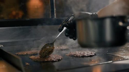 The chef in the kitchen of the restaurant makes cutlets for burgers - smash burger beefsteak