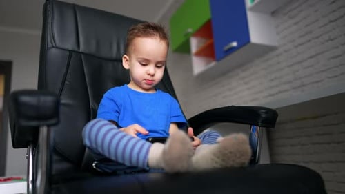 Child Using Smartphone Sitting in Black Leather Chair