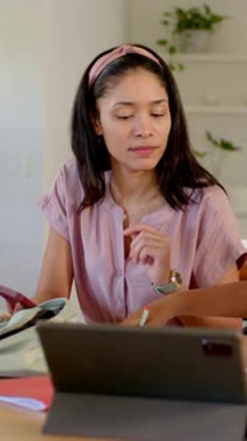 Vertical video: Noticing child writing, mom in pink top helping at home table with tablet, pencil