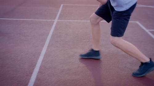 The Guy Basketball Player Dribbles the Ball Between the Legs in the Open Area Throwing the Ball