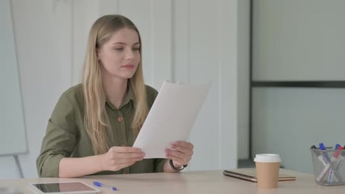 Woman Celebrates Reading Good News at Office Desk