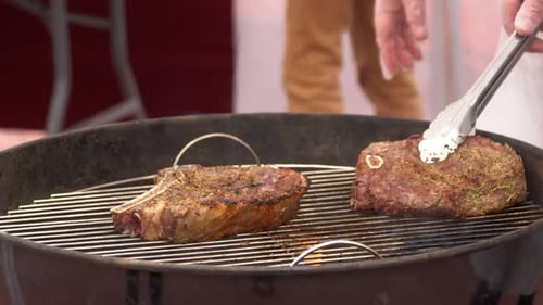 Chef Grilling and Turning Steaks on Barbecue Grill