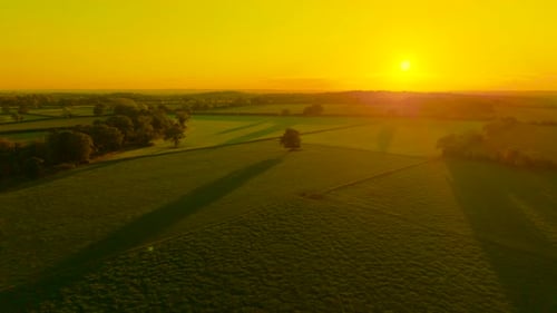 Sun Setting Over Rolling Farmlands of England Bathing Fields in Golden Light Long Shadows Fall
