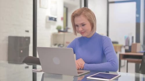 Young Woman Chatting Online on Laptop while Sitting in Office