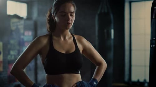 Portrait of a Beautiful Fit Brunette Kickboxer Standing in Loft Gym with Motivational Posters. She'