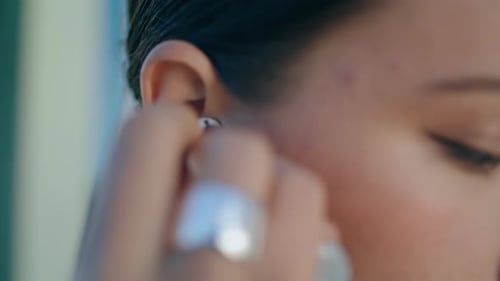 Woman Puts Wireless Earbud In Ear, Close Up