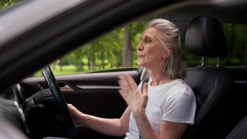 Une vieille femme caucasienne souffrant d'étouffement par la chaleur à l'intérieur d'une voiture soufflant avec les mains