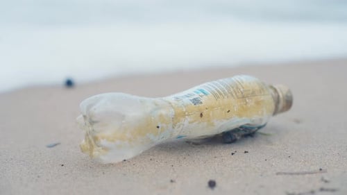 Rubbish washed up on a remote beach in far northern Australia. An old plastic bottle on the sand. Fi
