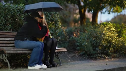A Loving Couple is Sharing a Cozy Umbrella While Enjoying the Beautiful Evening Park Ambiance