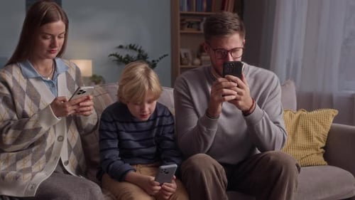Family Using Phones Together on the Couch at Home