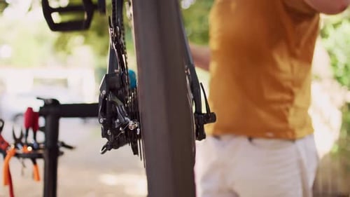 Adult Fixing Black Bicycle Outside in Greenery