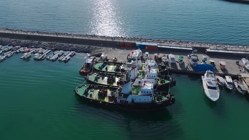 Luftbild von im Hafen festgemachten Schleppern mit Industriekränen und Frachtschiffen im Hintergrund