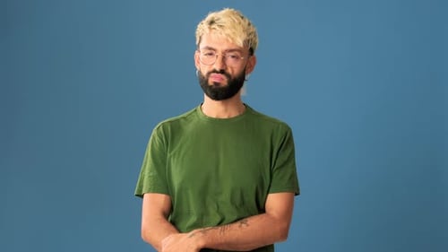Young man listens carefully and disagrees, isolated on blue background in a studio