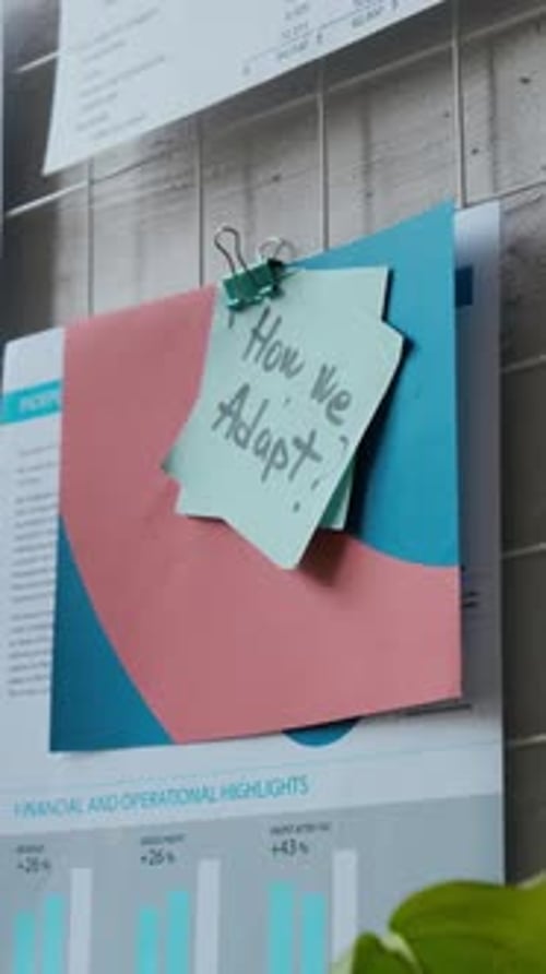 Sticky Note with Handwritten Message on Top of Paper Documents with Graphs