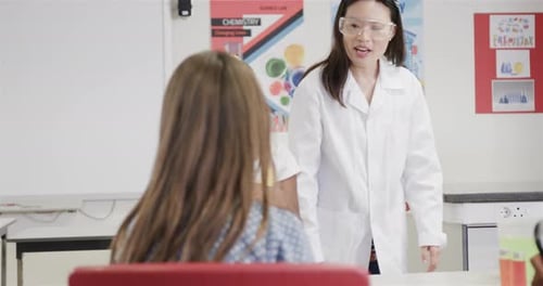 Diverse female teacher and girls doing experiments in elementary school chemistry class, slow motion
