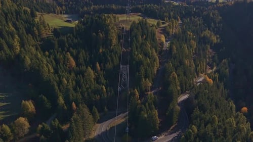 Cable car soaring above alpine landscape in sunshine, aerial shot.