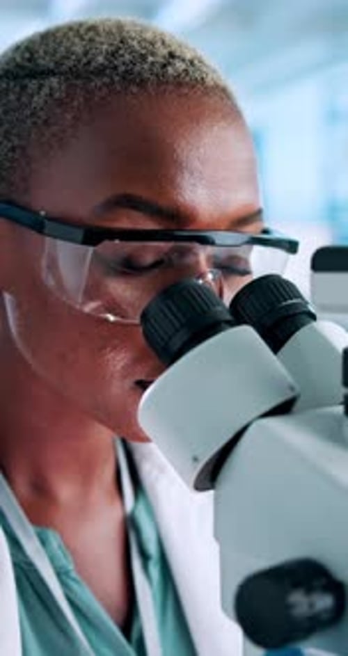 Woman Analyzing Sample Through Microscope in Modern Lab