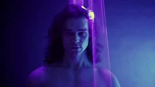 Sportlicher gutaussehender Mann mit langen Haaren, Portrait unter bunter Beleuchtung, Laserlicht, Neon Smoke Club