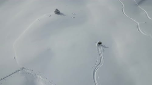 Luftaufnahme folgt jungen Sportskifahrern in verschneiten Alpen die schneebedeckte Gletschergebirgslandschaft hinunter