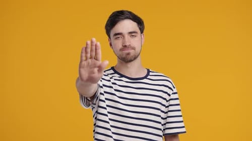 Portrait Of Serious Man In Striped TShirt Showing Rejecting Gesture Stop Palm