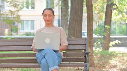 Woman Using Laptop in Park Reacts with Surprise