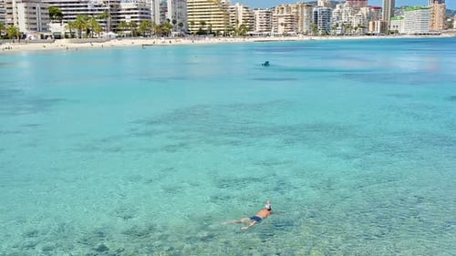 Menschen schwimmen im Meer in der Nähe der Küste von Calpe in Spanien. Stadtgebäude und klarer Himmel