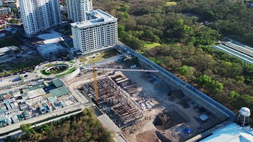 Zumbido desde arriba de una zona de construcción y una grulla amarilla rodeada de edificios y árboles de la ciudad i