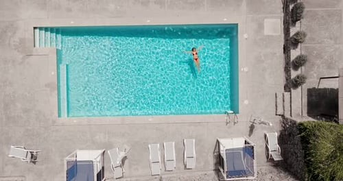 Top Down View of a Woman in Pink Swimsuit Lying on Her Back in the Pool