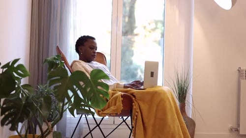 mulher africana de cabelo curto em casa com laptop trabalhando em casa