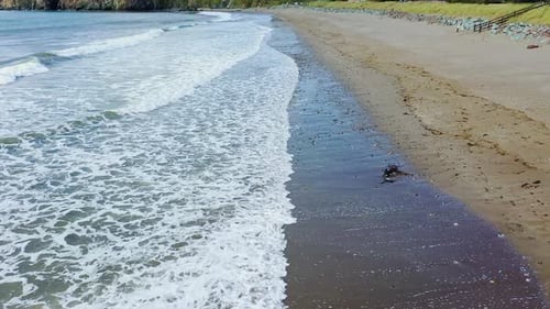 Aerial view of waves rolling in on a quiet sandy beach in the south of Ireland in Summertime