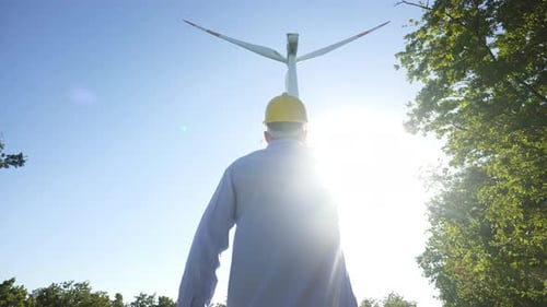 An young engineer is checking a correct operation and efficiency of windmills on a sunset. Concept