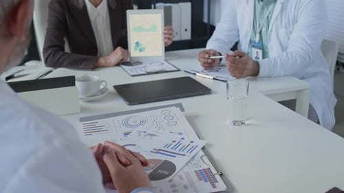 Doctor Reviewing Charts and Discussing Data with Clinic Director in Office