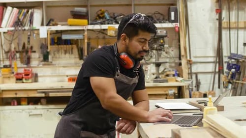 Male Carpenter Working at Laptop on Workshop Workbench 3539 Years