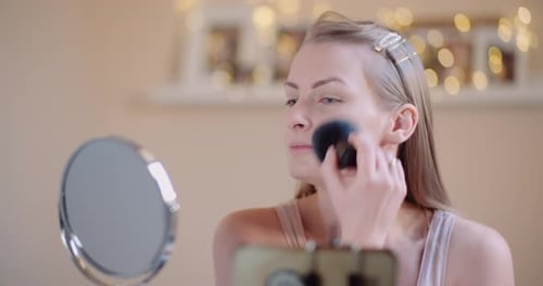 Woman Applying Makeup with Brush in Mirror