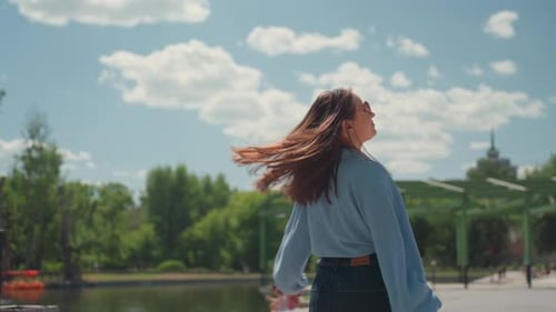 Happy Woman in Jeans Spinning Joyfully Beneath Open Sky and Park Delighted Woman in Denim Fabric