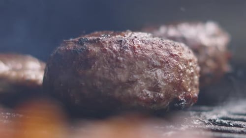 Statische Aufnahme von dickem, großem Rinder-Burger-Patty, das auf einem heißen Eisengrill zubereitet wird.