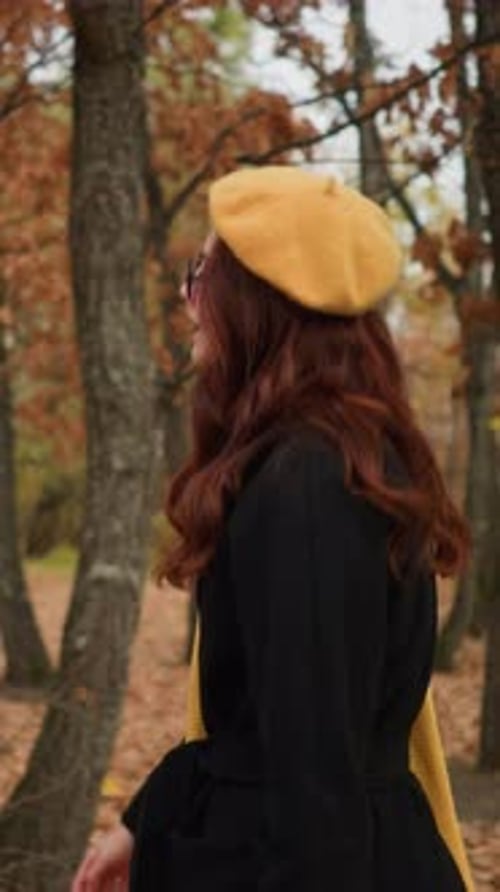 Stylish Lady Strolling Through Autumn Forest in Yellow Beret and Black Coat