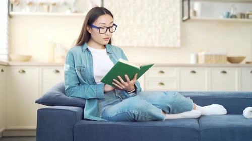 Woman Reading Book on Couch in Living Room