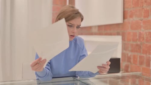 Woman Anxiously Reviews Documents Indoors