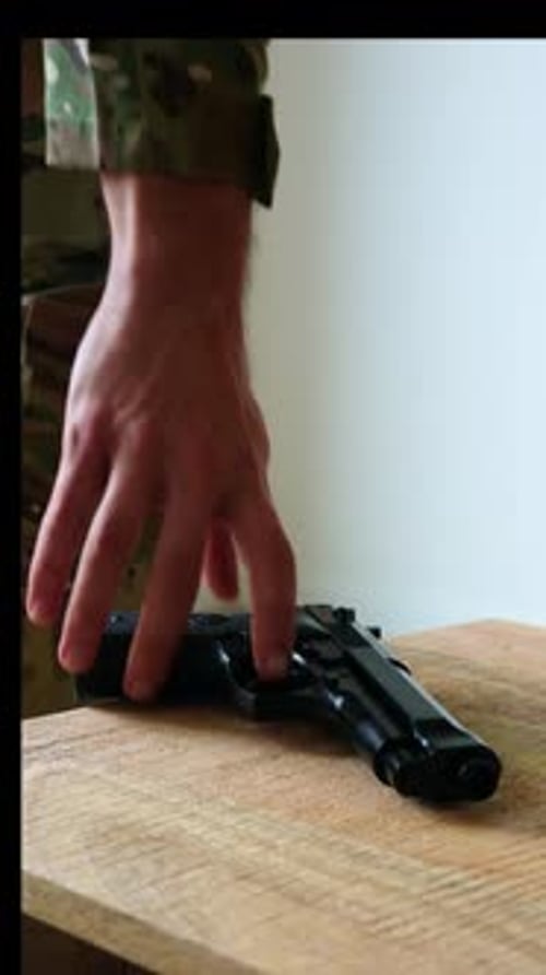 Hand Picks Up Pistol From Table