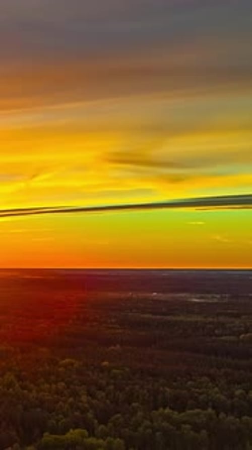 La bande chaude du lever du soleil s'étend à travers l'horizon au-dessus des champs et des forêts