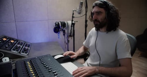 Mann arbeitet im Tonstudio mit Computer und Mixer und kreiert Musik im Tonstudio