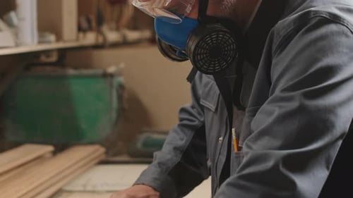 Woodworker Polishing Wooden Planks in Workshop