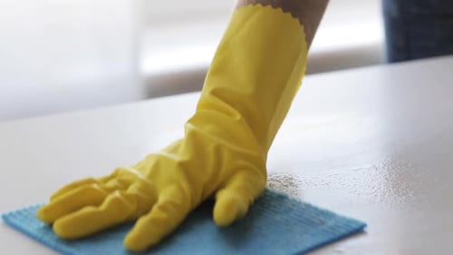 Cleaning and disinfecting white table with spray