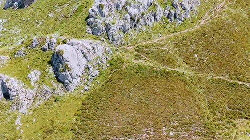 High rocks covered with grass and mosses. Blue lake at the foot of the mountain.