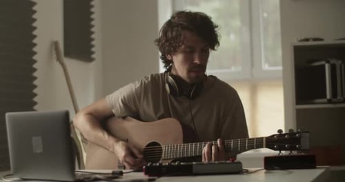 Adult Musician with Guitar at Desk in Studio
