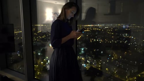 Woman Using Smartphone in Apartment at Night