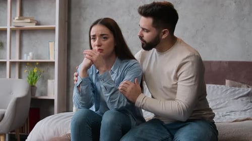 Supportive Man Comforts Distressed Woman on Bed